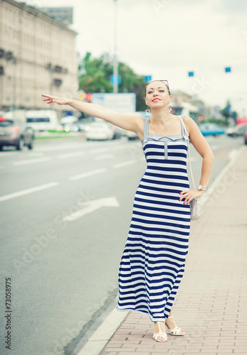 Young beautiful woman trying to hail a cab in the city