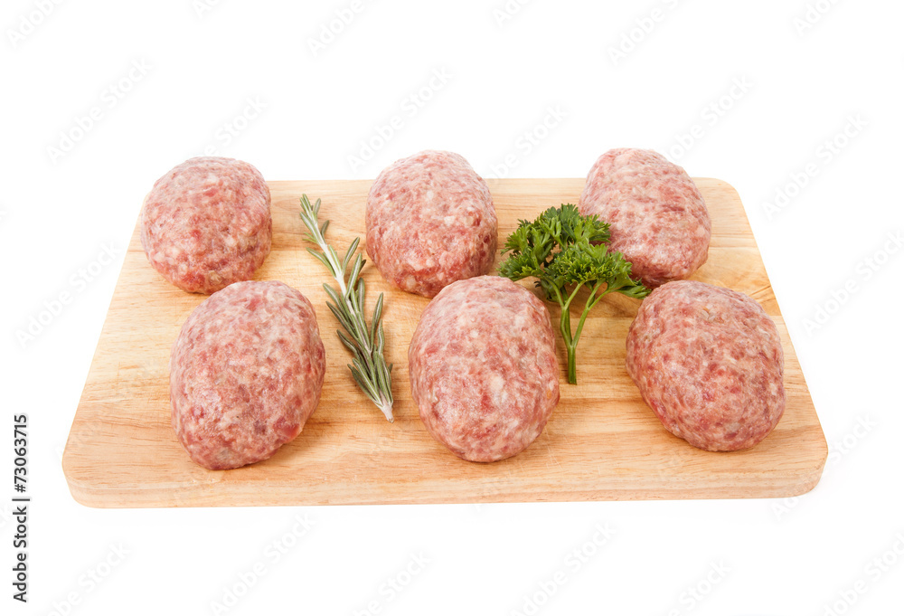 fresh uncooked patties on a wooden board with rosemary and parsl fresh uncooked patties on a wooden board with rosemary and parsl
