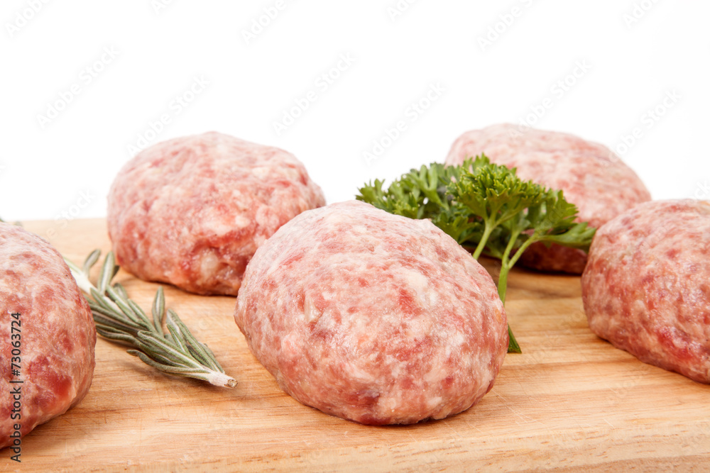 fresh uncooked patties on a wooden board with rosemary and parsl fresh uncooked patties on a wooden board with rosemary and parsl
