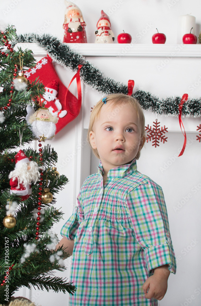 Cute surprised little girl stands near the Christmas tree Cute surprised little girl stands near the Christmas tree