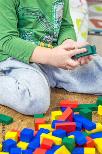 child is playing with multicolored cubes on wooden floor