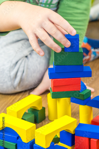 child is playing with multicolored cubes on wooden floor