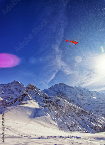 Red helicopter in the sky at swiss alps near Jungfrau mountain