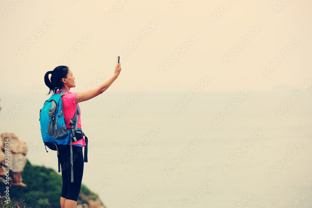 young woman hiker use smart phone taking photo at mountain peak young woman hiker use smart phone taking photo at mountain peak