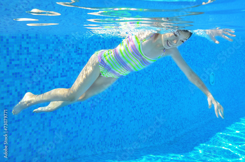 Happy active underwater child swims in pool  girl swimming