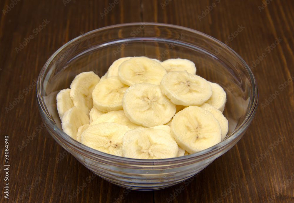 Banana slices in glass bowl on wooden table Banana slices in glass bowl on wooden table