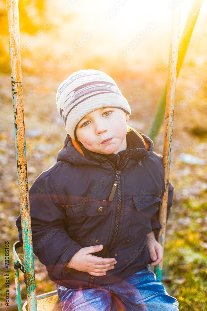 Boy swinging on a swing in a sunny autumn day Boy swinging on a swing in a sunny autumn day