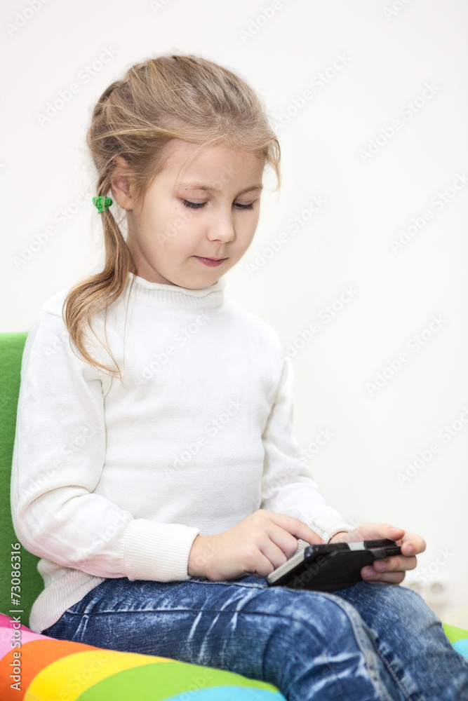 Child playing game on the cellphone, sitting indoor Child playing game on the cellphone, sitting indoor