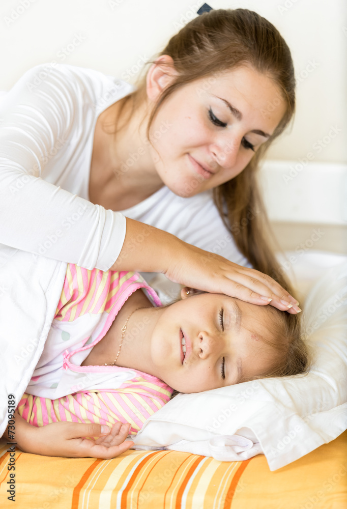 mother holding hand on sleeping daughter with care mother holding hand on sleeping daughter with care
