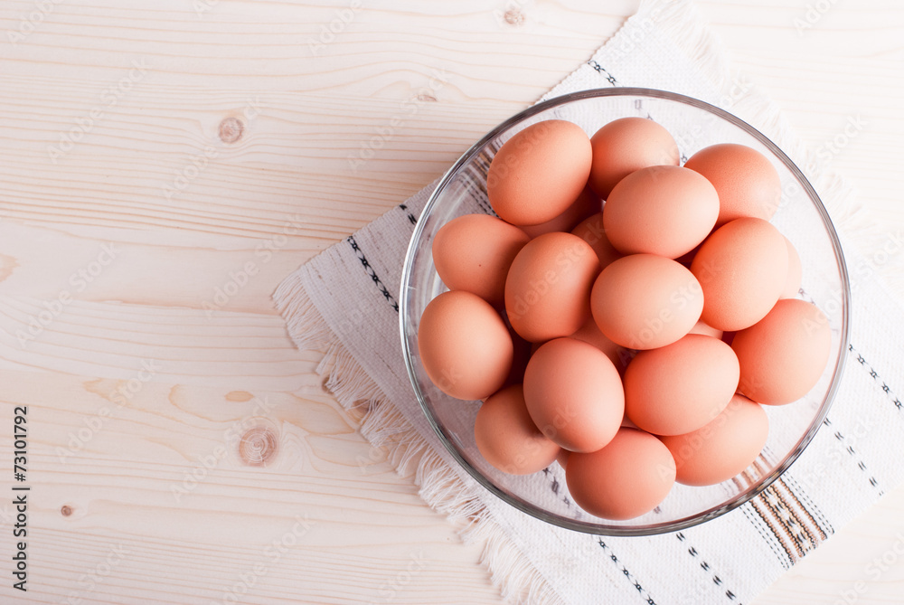 brown eggs in a large glass bowl on a light wooden table view brown eggs in a large glass bowl on a light wooden table view
