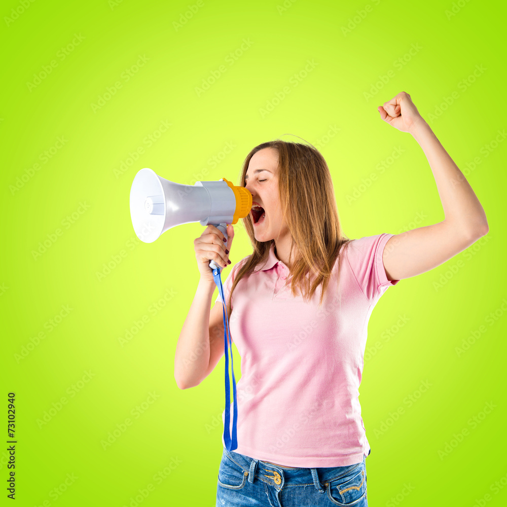Blonde girl shouting with a megaphone over green background Blonde girl shouting with a megaphone over green background