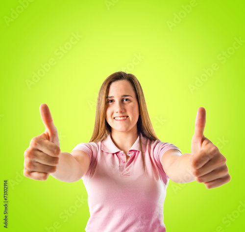Young girl making Ok sign over green background © luismolinero