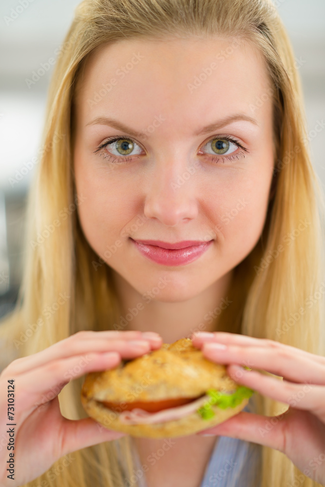 Portrait of young woman holding sandwich