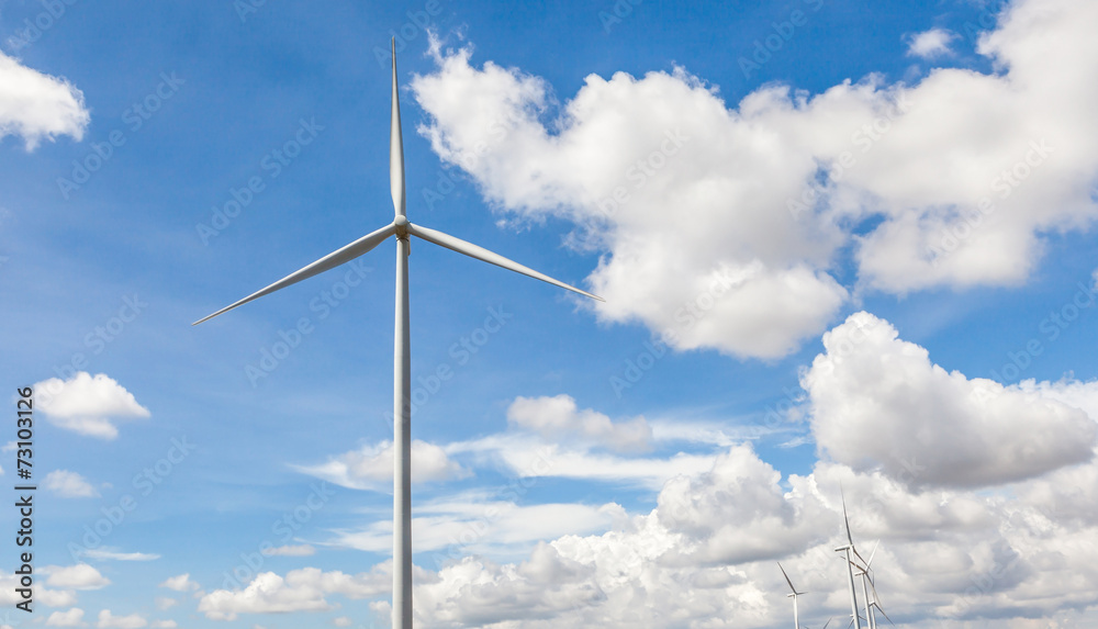 The giant wind turbine stands against cloudy blue sky background The giant wind turbine stands against cloudy blue sky background