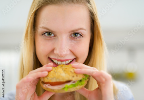Portrait of happy young woman eating sandwich