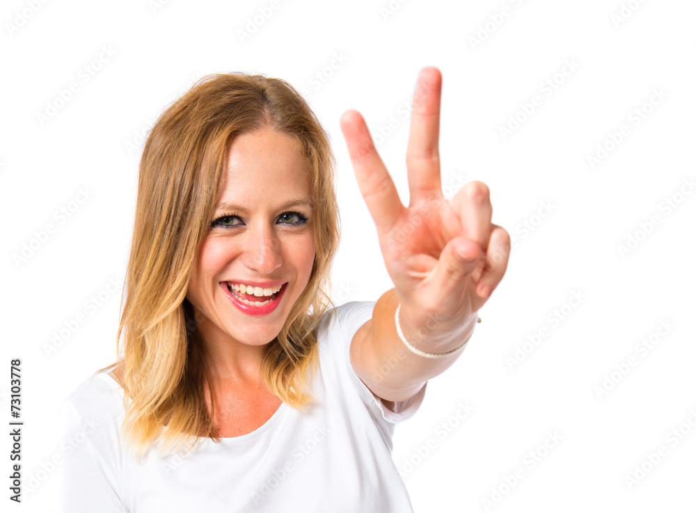 Cute woman doing victory gesture over white background Cute woman doing victory gesture over white background