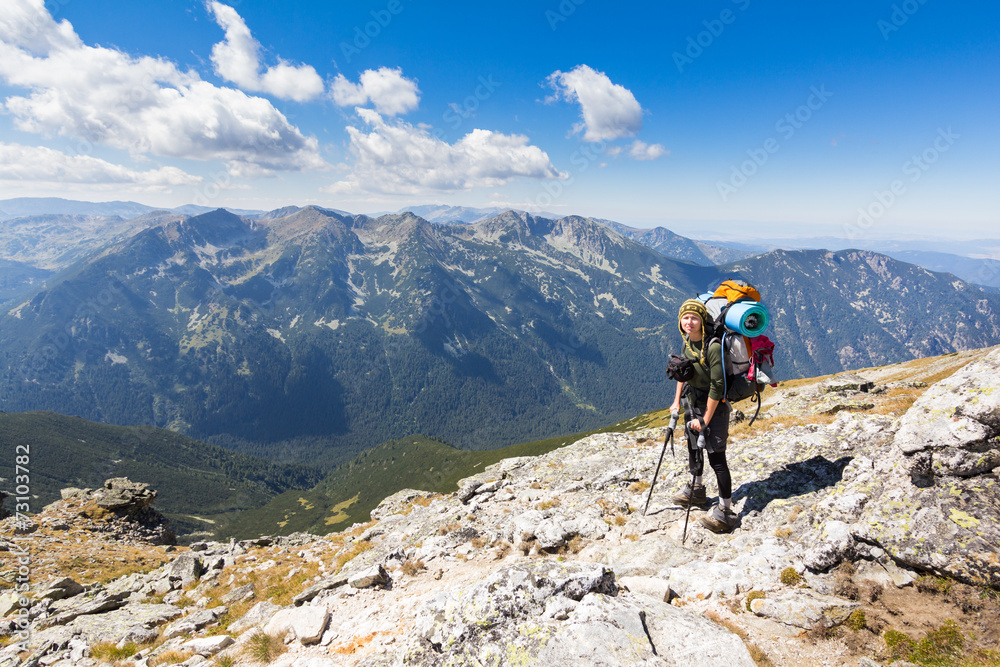 Woman backpacker standing mountain edge.