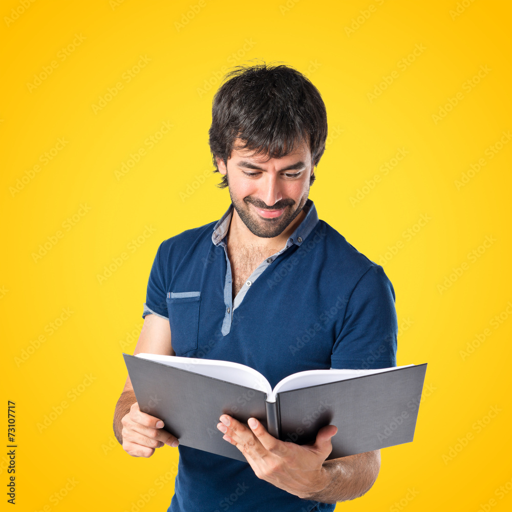 Man reading a book over yellow background Man reading a book over yellow background