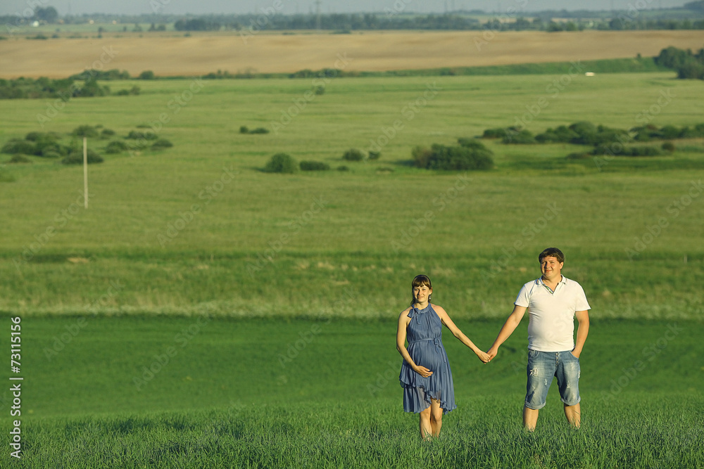 Fototapeta premium man and a pregnant woman in a summer field
