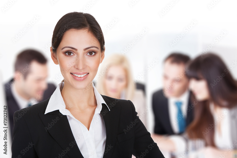 Smiling Businesswoman Against Team Discussing In Boardroom Smiling Businesswoman Against Team Discussing In Boardroom