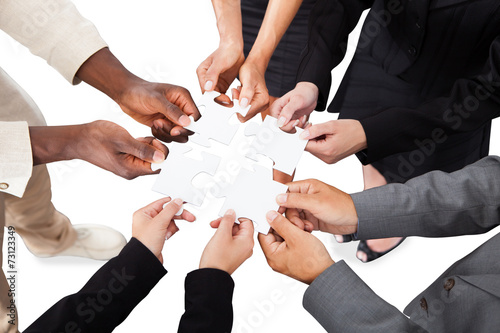 Business People's Hands Solving Jigsaw Puzzle