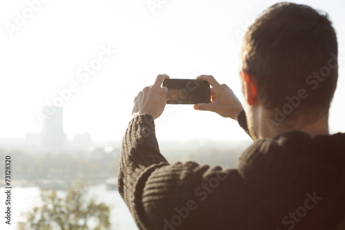 Man Taking Photo Of City And River With Mobile Phone Outdoor