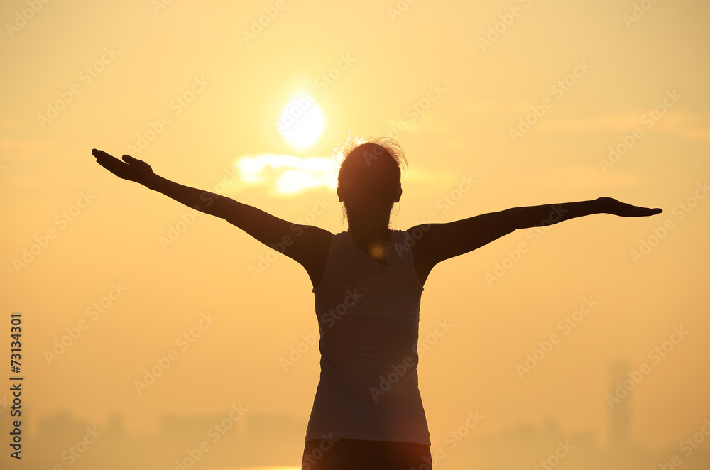 woman open arms under the sunrise at sea 
