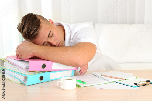 Tired man with many folders sleeps on table