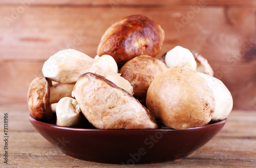 Wild mushrooms on plate on wooden background