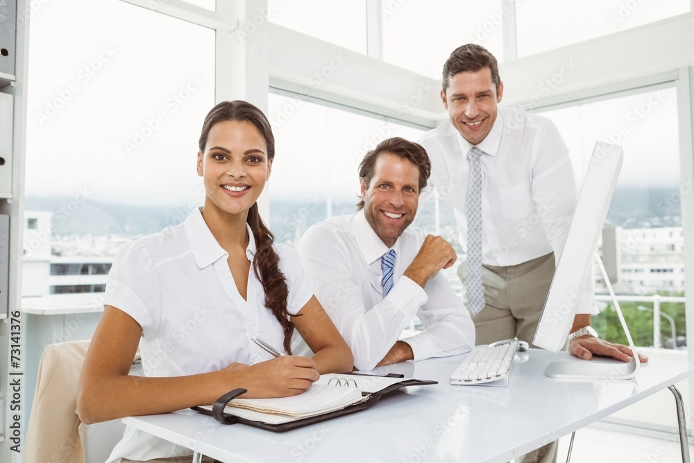 Fototapeta premium Three smiling business people at office desk