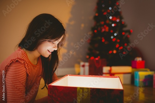 Little girl opening a glowing christmas gift