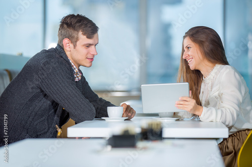 Flirting couple in cafe using digital tablet, selective focus