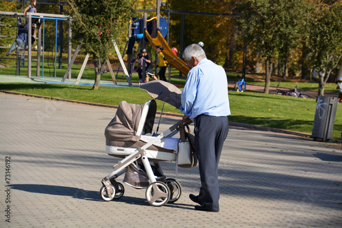 abuelo paseando con un carrito de niño © uzkiland