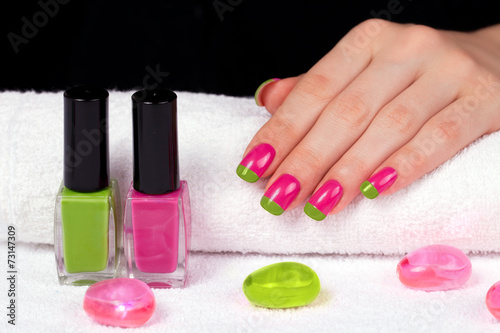 Female hand with two-color manicure on towel on black background