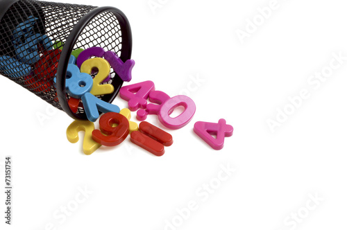 Colorful plastic numbers in black metal container isolated on wh