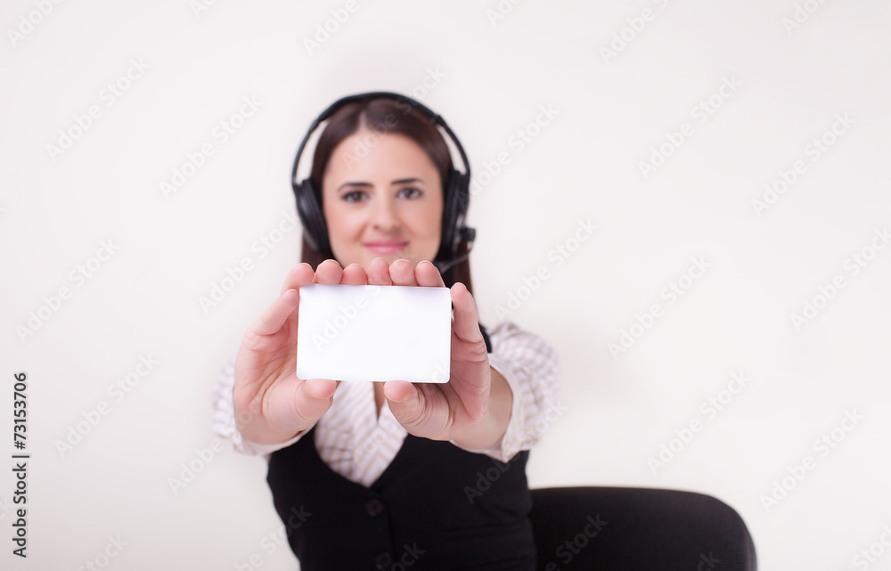 Young businesswoman wearing a headset holding out a blank white Young businesswoman wearing a headset holding out a blank white