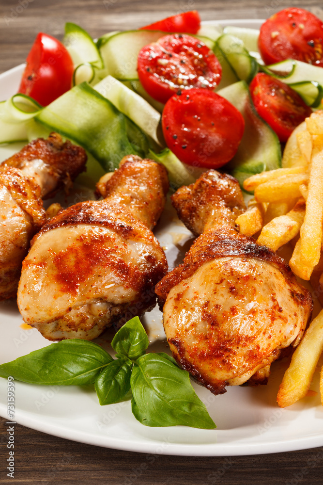 Grilled chicken legs with chips and vegetables