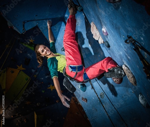 Young woman practicing rock-climbing on a rock wall indoors