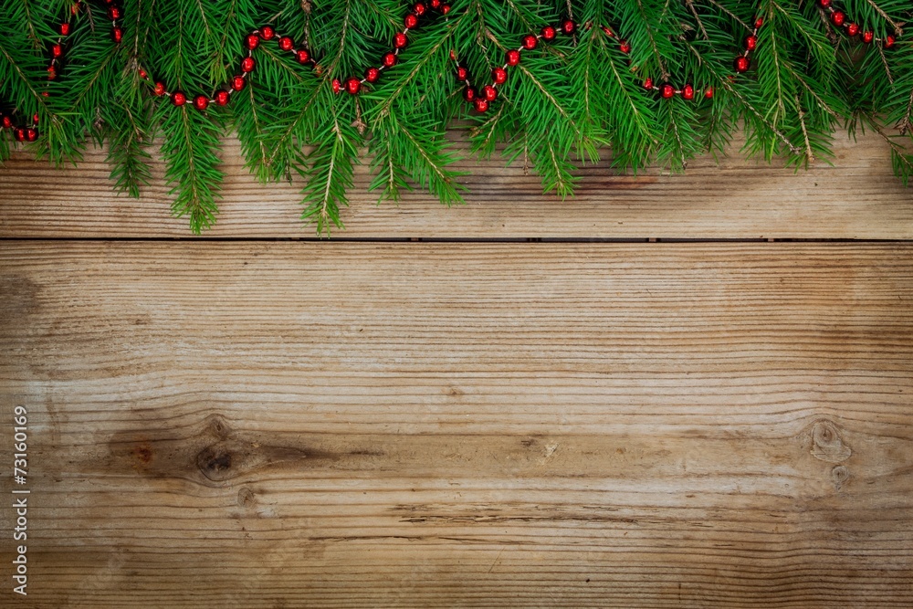 Pine tree border with red garland on old wooden background Pine tree border with red garland on old wooden background