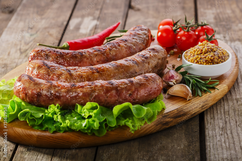 Grilled sausage on a board with vegetables and sauce Grilled sausage on a board with vegetables and sauce