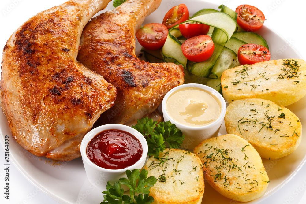 Barbecued chicken legs with baked potatoes and vegetables