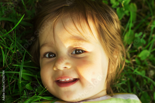 little kid resting on a green grass