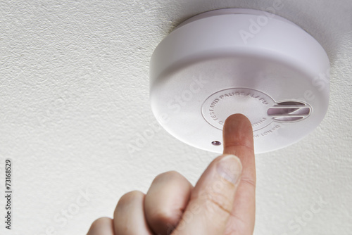 Close Up Of Hand Testing Domestic Smoke Alarm photo