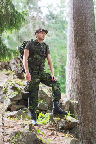 young soldier with backpack in forest