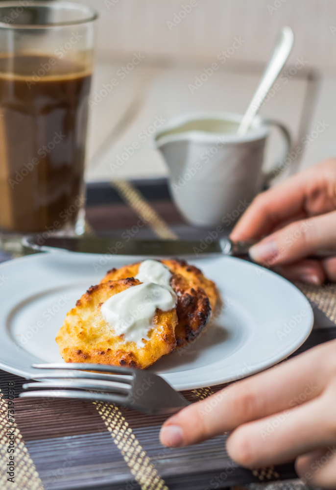 eat curd cheese pancakes with sour cream for breakfast, hands eat curd cheese pancakes with sour cream for breakfast, hands