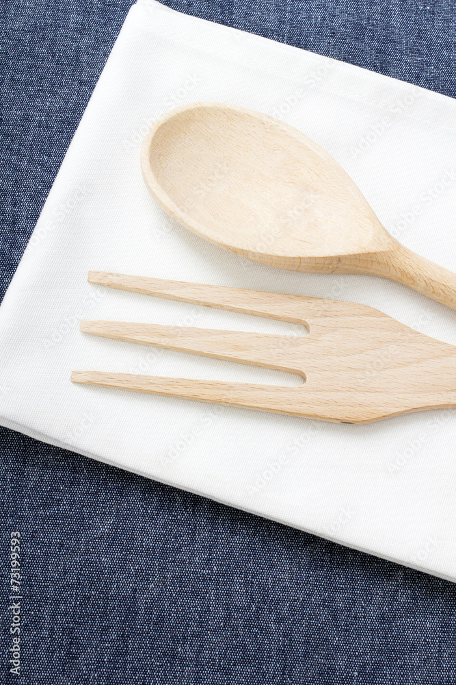 wooden spoon and fork placed on a white napkin.