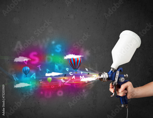 Worker with airbrush and colorful abstract clouds and balloons