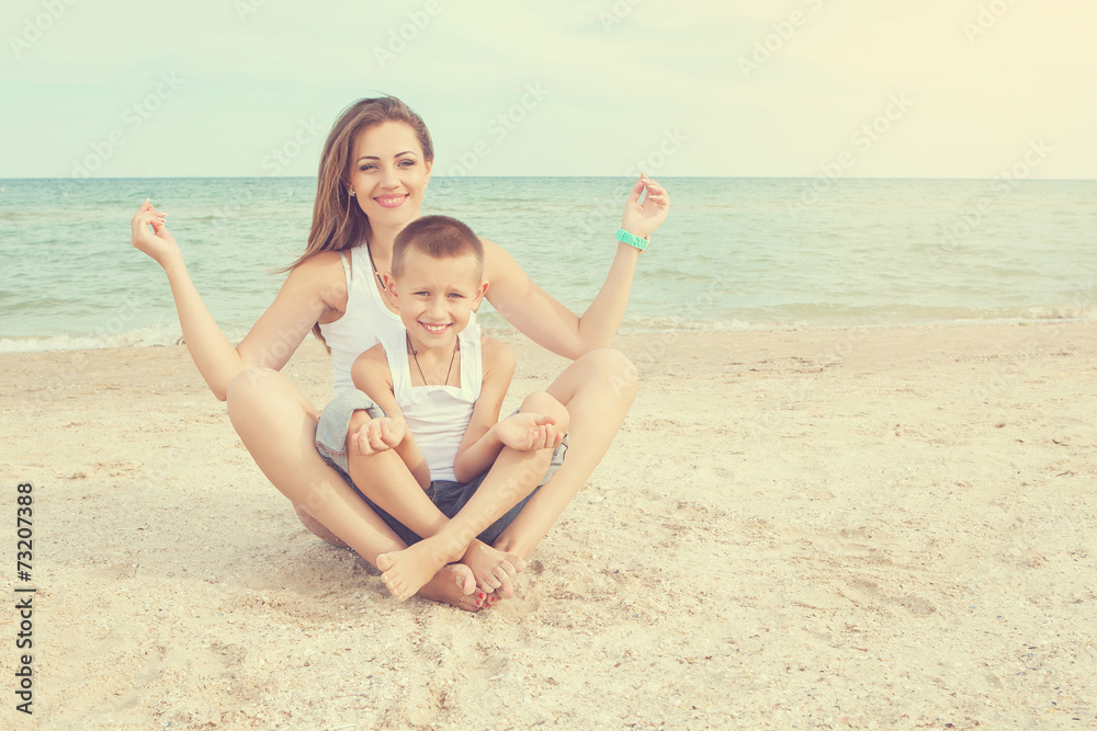 Mother and her son doing yoga on coast of sea on beach. Mother and her son doing yoga on coast of sea on beach.