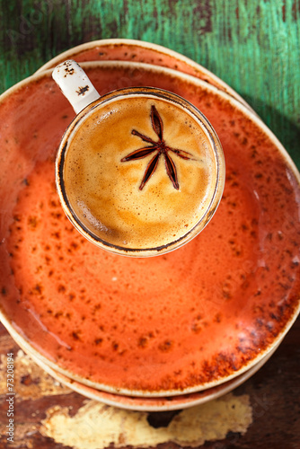 A cup of spiced coffee with anise star and soucers photo