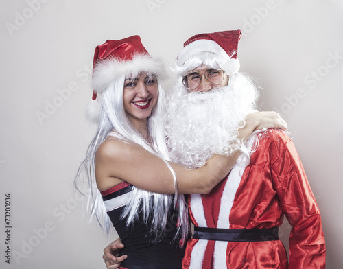 Santa Claus and girl wearing Christmas hat smiling